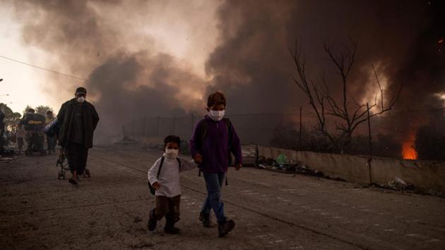 Two children leave after the second fire broke out in the Moria migrants camp on September 9. Greek authorities transferred 406 unaccompanied minors to safe locations the mainland early on September 10, the Greek Prime Minister’s office said. (Angelos Tzortzinis / AFP) Two children leave after the second fire broke out in the Moria migrants camp on September 9. Greek authorities transferred 406 unaccompanied minors to safe locations the mainland early on September 10, the Greek Prime Minister’s office said. (Angelos Tzortzinis / AFP)