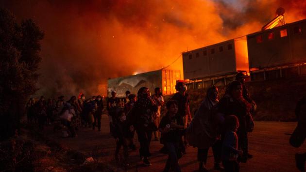 People flee flames after another fire broke out in the Moria migrants camp on September 9. This second fire late on September 9 destroyed most of what remained unscathed from the previous night and housed another 8,000 people living in tents and makeshift shacks around the perimeter, the Greek migration ministry said in a statement. (Angelos Tzortzinis / AFP) People flee flames after another fire broke out in the Moria migrants camp on September 9. This second fire late on September 9 destroyed most of what remained unscathed from the previous night and housed another 8,000 people living in tents and makeshift shacks around the perimeter, the Greek migration ministry said in a statement. (Angelos Tzortzinis / AFP)