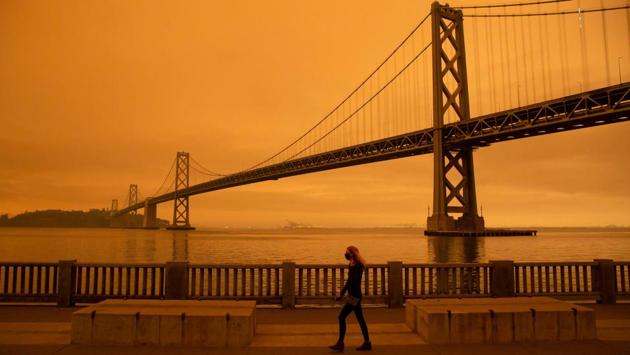 A woman walks along the Embarcadero under an orange, smoke-filled sky in San Francisco on September 9. According to the Bay Area Air Quality Management District spokesman Ralph Borrmann, smoke particles above the marine layer were acting like a filter, scattering blue light and only allowing yellow, orange and red light to reach the ground, AP reported. (Brittany Hosea-Small / AFP)