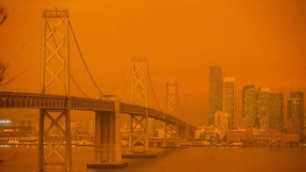 The San Francisco Bay Bridge and the city skyline are obscured by orange smoke and haze as seen from Treasure Island in San Francisco, California on September 9. Hazy clouds of smoke from dozens of wildfires darkened the sky to an eerie orange glow over much of the West Coast on September 9, keeping street lights illuminated during the day and putting residents on edge. (Brittany Hosea-Small / AFP)