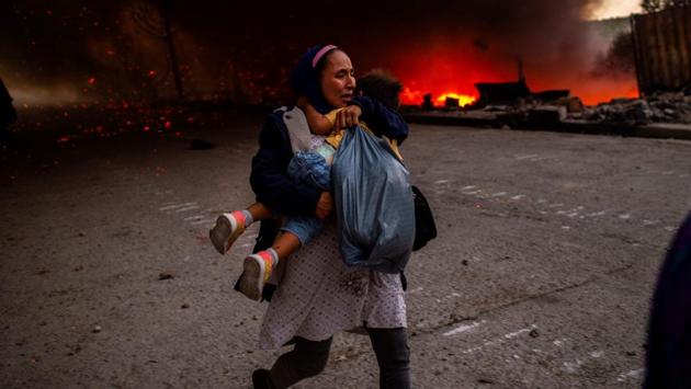 A woman flees with a little girl in front of a fire burning in the Moria camp for migrants on the Greek island of Lesbos on September 9. Thousands of asylum seekers escaped in panic and are camping in the open after two fires ripped through the camp of Moria, the country's largest and most notorious migrant facility. (Angelos Tzortzinis / AFP) A woman flees with a little girl in front of a fire burning in the Moria camp for migrants on the Greek island of Lesbos on September 9. Thousands of asylum seekers escaped in panic and are camping in the open after two fires ripped through the camp of Moria, the country's largest and most notorious migrant facility. (Angelos Tzortzinis / AFP)