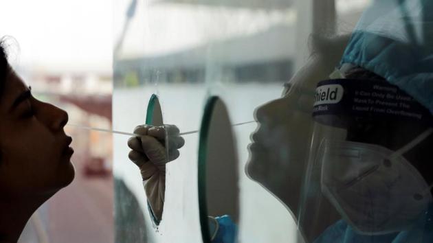 A health worker in PPE collects a swab sample amidst the spread of the coronavirus disease, at Indira Gandhi International Airport in New Delhi on Saturday.(Reuters Photo)