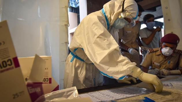 A healthcare worker gets ready to collect swab samples from people for coronavirus testing, in Shadipur, in New Delhi on Sunday. (Sanchit Khanna/HT Photo)