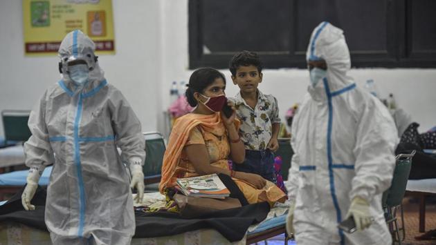 Health workers wearing PPE coveralls walk past Covid-19 patients inside the Commonwealth Games (CWG) Village Covid-19 care centre in New Delhi on September 13. The Central government has directed states to focus on districts that are reporting high CFR. It has also asked the states to strengthen their approach and strategies relating to testing, contact tracing, home isolation, availability of ambulances, hospital beds, oxygen, HT reported. (Biplov Bhuyan / HT Photo)