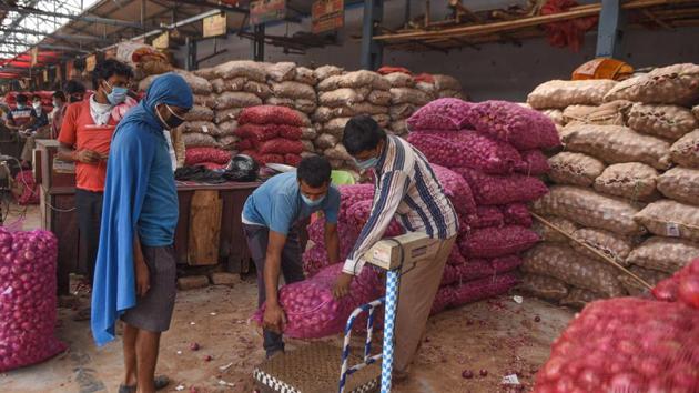 Workers weighing a sack onions during the nationwide lockdown. (Sanchit Khanna/HT PHOTO)