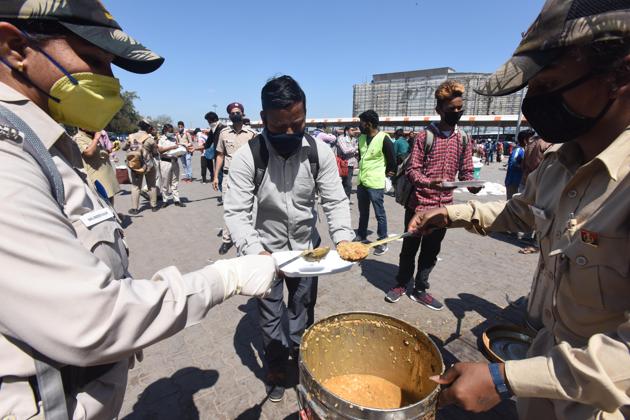 Civil defence personnel offer food to migrant workers heading home, Anand Vihar Bus Terminus, Delhi, March 28, 2020(Raj K Raj/HT PHOTO)