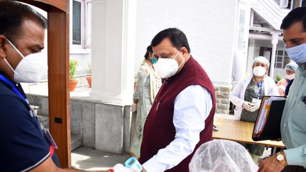 Security personnel check the body temperature of rural development and panchayati raj minister Virender Kanwar before going to attend the monsoon session in Shimla on Monday.(Deepak Sansta / HT)