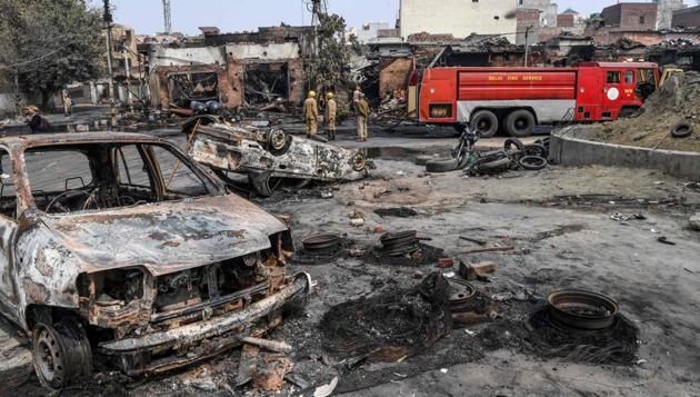 Firefighters stand near a fire rescue vehicle as they douse burnt-out vehicles and buildings in northeast Delhi in February.(AFP)