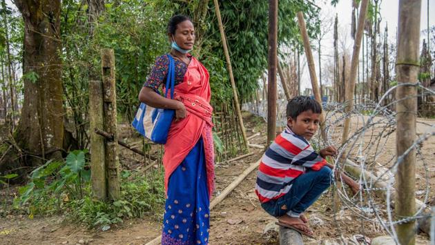 Anju Bora and her son look on at their abandoned house from a barricade near the gas well blowout site in Baghjan on September 11. In the village of nearly 500 residents, many earned their living by fishing, tilling their fields, some with betel nut trees, and working in the tea gardens close by. Now the village is ruined, said locals, estimating that several homes have been completely burnt and about 500 hectares of land destroyed. (Manish Sharma / PTI)