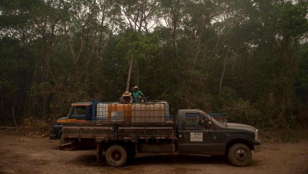 Volunteers and Panthera NGO workers stand in a water truck as they help firefighters from the Mato Grosso State Department combatting a nearby wildfire, in the Porto Jofre region in the wetlands of the Pantanal near the Transpantaneira park road in Mato Grosso state, Brazil, on September 14. (Mauro Pimentel / AFP)