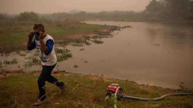 Volunteer Antonio Jose da Silva, 50, collects water from a river beside alligators to combat a wildfire as he and other volunteers try to protect a wooden bridge in the wetlands of the Pantanal at the Transpantaneira park road in Mato Grosso state, Brazil, on September 14. A record 23,490 square kilometers have burned through Sept. 6 - nearly 16% of the Brazilian Pantanal, according to a Federal University of Rio de Janeiro analysis, reported Reuters. (Mauro Pimentel / AFP)