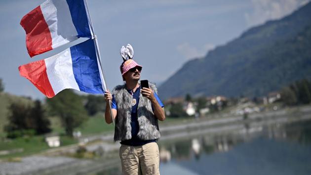 A fan films the riders as he waves a French flag while the cyclists race between Grenoble and Meribel in France on September 16. Vehicles have also been banned which means people will be unable to set camp unlike previous years, AFP reported. (Anne-Christine Poujoulat / AFP)