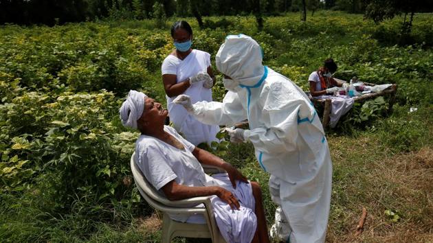 A healthcare worker wearing personal protective equipment (PPE) takes swabs from a farmer in a field, amidst the coronavirus disease (Covid-19) outbreak in Gujarat.(REUTERS)