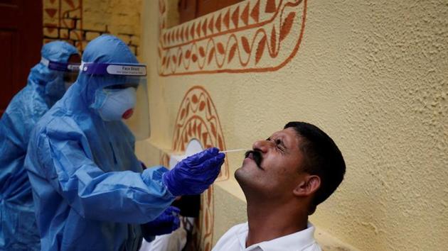 A healthcare worker wearing personal protective equipment (PPE) takes a swab from a police officer for a rapid antigen test.(Reuters Photo)