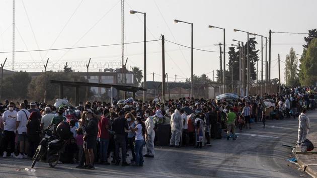 Men, women and children with bundles on their backs line up ahead of a police barricade on the road before entering the temporary camp in Kara Tepe on the island of Lesbos on September 18. (Petros Giannakouris / AP) Men, women and children with bundles on their backs line up ahead of a police barricade on the road before entering the temporary camp in Kara Tepe on the island of Lesbos on September 18. (Petros Giannakouris / AP)