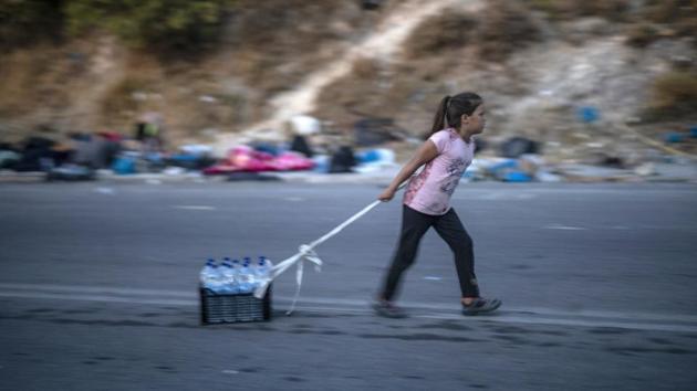A migrant pulls a crate with bottles of water on the island of Lesbos on September 18. Migration Minister Notis Mitarachi told reporters at the camp that some 5,000 people had entered the temporary camp by September 17 afternoon and relocating the remaining 7,000 homeless asylum seekers who have so far stayed away would take “a few days.” (Petros Giannakouris / AP) A migrant pulls a crate with bottles of water on the island of Lesbos on September 18. Migration Minister Notis Mitarachi told reporters at the camp that some 5,000 people had entered the temporary camp by September 17 afternoon and relocating the remaining 7,000 homeless asylum seekers who have so far stayed away would take “a few days.” (Petros Giannakouris / AP)