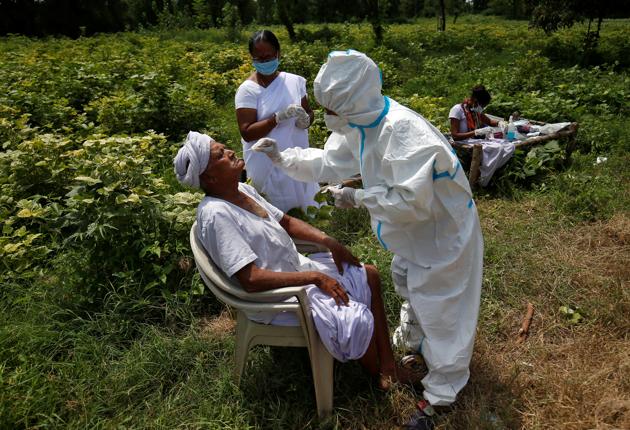 A healthcare worker wearing personal protective equipment (PPE) takes swabs from a farmer in a field, amidst the coronavirus disease (Covid-19) outbreak in Gujarat, India.(REUTERS)