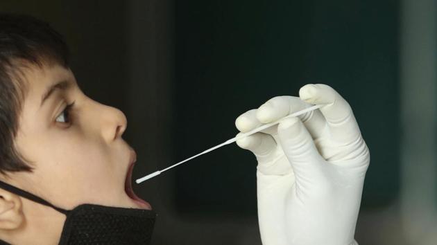 A health worker collects a swab sample to test for Covid-19 at a government hospital in Jammu. (AP) A health worker collects a swab sample to test for Covid-19 at a government hospital in Jammu. (AP)