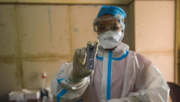 A health worker in PPE coveralls shows a testing slide while collecting swab samples for coronavirus testing at Saket in New Delhi (Photo by Amal KS/ Hindustan Times)