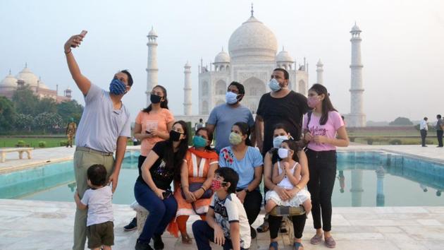 A family takes a selfie in front of the Taj Mahal after it reopened to the general public in Agra on September 21. Amid other safety measures prescribed, visitors can only take off their masks for a photo and the famous bench where people usually sit to have their picture taken has been laminated in plastic, to help cleaning between every photo opportunity. (ANI) 