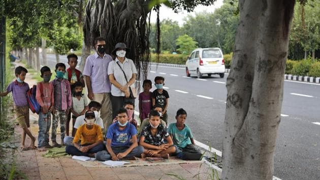 A former diplomat Virendra Gupta and his singer wife Veena Gupta pose for a photograph with underprivileged children whom they teach on a sidewalk in New Delhi, India, on Sept. 3, 2020. The Indian couple are conducting free classes for underprivileged children on a sidewalk in New Delhi with the goal to keep them learning and not left behind when schools reopen. As most schools in India remain shut since late March when the country imposed a nationwide lockdown to curb the spread of COVID-19, many switched to digital learning and taking classes online.(AP)
