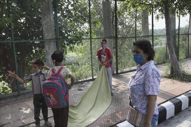Children lay a sheet to sit on for their class on a sidewalk as their teacher Veena Gupta watches in New Delhi, India, on Sept. 3, 2020. (AP) Children lay a sheet to sit on for their class on a sidewalk as their teacher Veena Gupta watches in New Delhi, India, on Sept. 3, 2020. (AP)