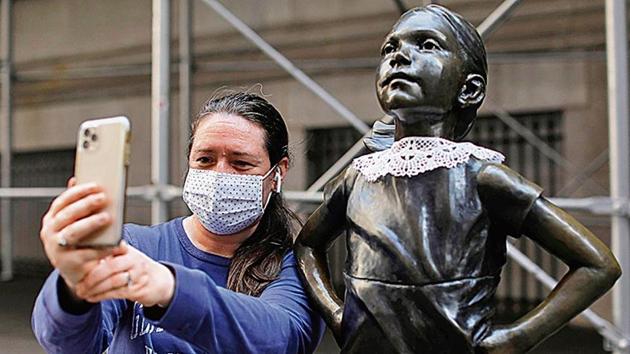 A woman takes a selfie with the Fearless Girl statue in Manhattan, New York City, after a jabot collar was placed on it in honour of late judge Ruth Bader Ginsburg.