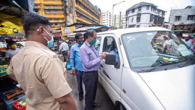 Brihanmumbai Municipal Corporation (BMC) officials along with Mumbai Police personnel issue challan to a commuter for not wearing a face mask at Colaba market in Mumbai on September 18. While both Delhi and Mumbai have opened up considerably in recent days, as part of the ongoing Unlock 4.0, most private offices are yet to resume working at full strength. (Pratik Chorge / HT Photo) 