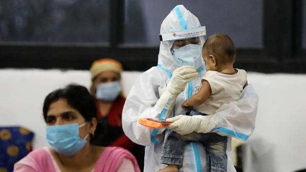 A medical worker in personal protective equipment (PPE) plays with a child of woman recovering inside a quarantine centre for the coronavirus disease patients amidst the spread of the disease at an indoor sports complex in New Delhi. (REUTERS)