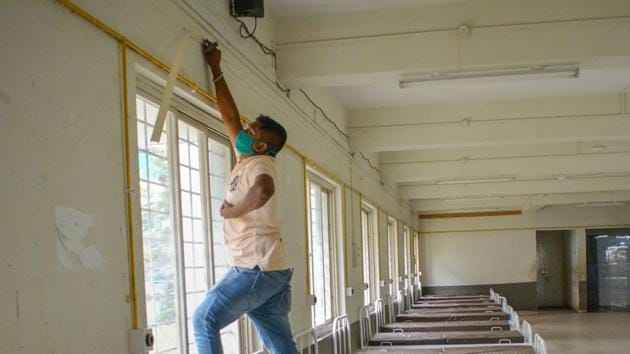 A worker installs lights inside the Yashwantrao Chavan Auditorium, converted into a COVID-19 care centre, in Karad.(PTI)