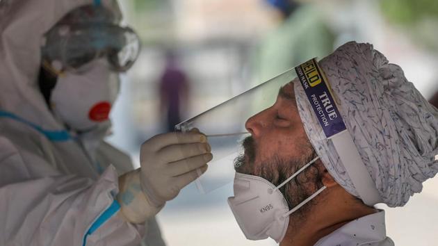 A health worker collects a nasal sample for Covid-19 test, at a government hospital in Jammu on Friday. (PTI) A health worker collects a nasal sample for Covid-19 test, at a government hospital in Jammu on Friday. (PTI)