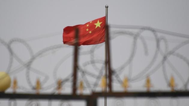 Chinese flag behind razor wire at a housing compound in Yangisar, south of Kashgar, in China's western Xinjiang region.(AFP)