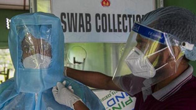 A health worker helps another to wear personnel protection equipment before he collects nasal swab samples at a Covid-19 testing centre in Guwahati.(AP Photo)