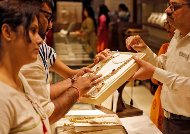 A salesman shows a gold necklace to customers at a jewellery showroom in Ahmedabad in this file photo.(Reuters Photo) A salesman shows a gold necklace to customers at a jewellery showroom in Ahmedabad in this file photo.(Reuters Photo)