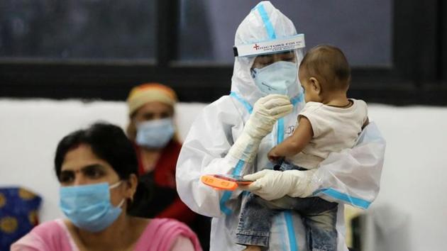 A medical worker in personal protective equipment (PPE) plays with a child of woman recovering inside a quarantine centre for the coronavirus disease (COVID-19) in New Delhi.(Reuters) A medical worker in personal protective equipment (PPE) plays with a child of woman recovering inside a quarantine centre for the coronavirus disease (COVID-19) in New Delhi.(Reuters)