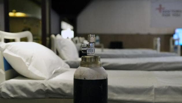 An oxygen cylinder sits next to a bed in a makeshift ward at an emergency Covid-19 care center set up in the Shehnai Banquet Hall at the Lok Nayak Jai Prakash Hospital Annexe in New Delhi.(Bloomberg)