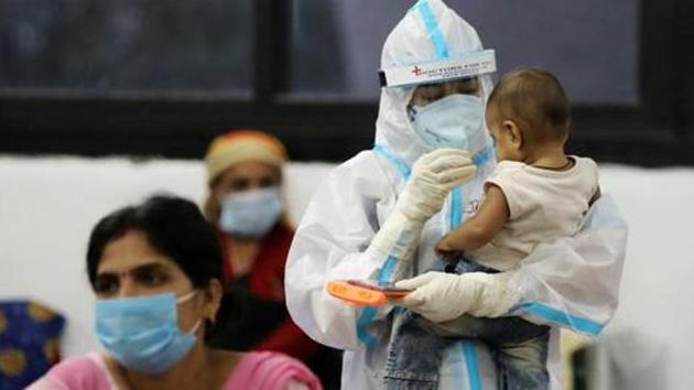 A medical worker in personal protective equipment (PPE) plays with the child of a woman recovering inside a quarantine centre from the coronavirus disease in New Delhi.(REUTERS PHOTO.) A medical worker in personal protective equipment (PPE) plays with the child of a woman recovering inside a quarantine centre from the coronavirus disease in New Delhi.(REUTERS PHOTO.)