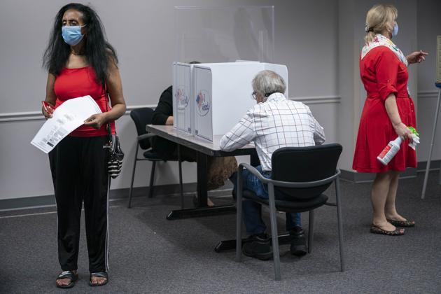 Voters wearing protective masks cast ballots at an early voting polling location in Fairfax, Virginia on September 18. Because of Covid-19 restrictions this has been a mostly long-distance election season. Early signs show voters are changing their behaviour as the shadow of the coronavirus hangs over the presidential race. President Trump has repeatedly raised postal voting as riddled with frauds without presenting much evidence. (Sarah Silbiger / Bloomberg) Voters wearing protective masks cast ballots at an early voting polling location in Fairfax, Virginia on September 18. Because of Covid-19 restrictions this has been a mostly long-distance election season. Early signs show voters are changing their behaviour as the shadow of the coronavirus hangs over the presidential race. President Trump has repeatedly raised postal voting as riddled with frauds without presenting much evidence. (Sarah Silbiger / Bloomberg)