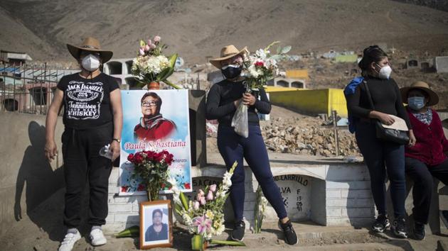 Rosario Carrillo (L), poses for a photograph with her daughter Daniela, next to the tomb of sister Paula Sebastian, who died due to COVID-19, at Martires 19 de Julio, in Comas, Peru on September 25. Overall, there are at least 33 million confirmed infections across the globe, according to worldometers.info. (Rodrigo Abd / AP)