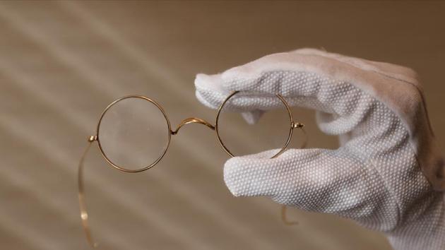 A member of staff holds a pair of round Windsor spectacles that belonged to John Lennon at Sotheby's auction house ahead of their "Beatles for Sale" auction in London.(REUTERS)