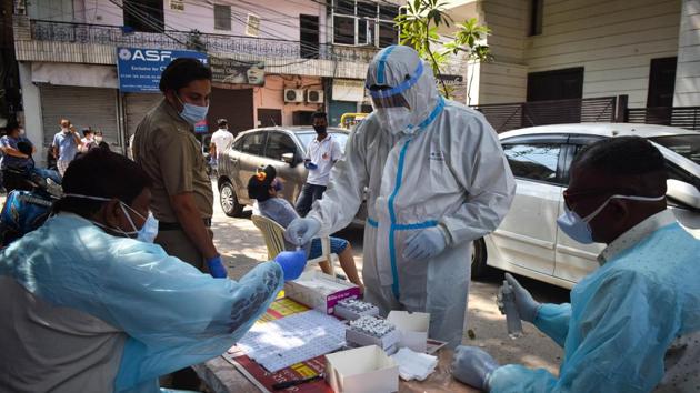 A health worker in PPE coveralls hands over a collected swab sample to colleagues during coronavirus testing, at Hudson Lane, in New Delhi on Sunday.(Sanchit Khanna/HT Photo) A health worker in PPE coveralls hands over a collected swab sample to colleagues during coronavirus testing, at Hudson Lane, in New Delhi on Sunday.(Sanchit Khanna/HT Photo)