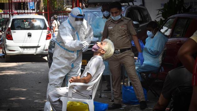 A health worker in PPE coveralls collects a swab samples for coronavirus testing, at Hudson Lane, in New Delhi on Sunday.(Sanchit Khanna/HT PHOTO)