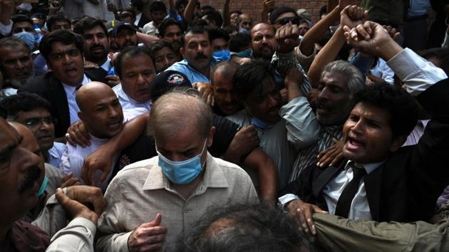 Shahbaz Sharif (Centre wearing blue mask), Pakistani opposition leader and brother of former prime minister Nawaz Sharif, comes out from the Lahore high court surrounded by supporters after the court rejected his bail plea in a money laundering and assets beyond income case.(AFP)