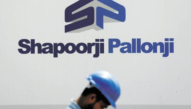 A construction worker walks past a hoarding of Indian conglomerate Shapoorji Pallonji Group on the outskirts of Mumbai.(Reuters File Photo)