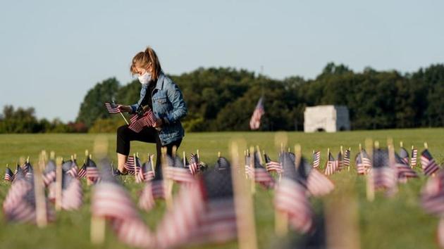 A volunteer places American flags representing some of the 200,000 lives lost in the United States in the coronavirus disease (Covid-19) pandemic on the National Mall in Washington.(REUTERS) A volunteer places American flags representing some of the 200,000 lives lost in the United States in the coronavirus disease (Covid-19) pandemic on the National Mall in Washington.(REUTERS)