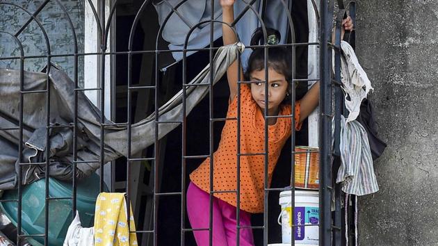 Mumbai: A girl looks on through the window of her house during a nationwide lockdown in the wake of coronavirus pandemic, at Dharavi in Mumbai (File Photo)(PTI)