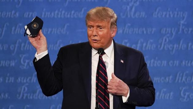 Trump holds up his face mask during the first 2020 US presidential debate on September 29. Hours before the debate, Biden released his 2019 tax returns and his campaign called on Trump, who has come under fire for not releasing his returns. On September 27, The New York Times had reported that Trump paid just $750 in federal income taxes in 2016 and 2017 and none in 10 of the previous 15 years. (Julio Cortez / AP)