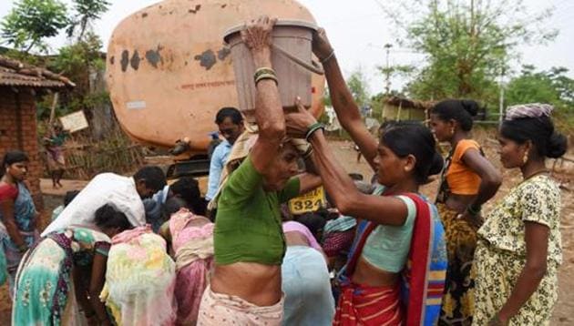 A woman assists an elderly to carry a bucket filled with tanker water at Shakar Pada village near Shahapur, on the outskirts of Mumbai.(AFP File Photo)