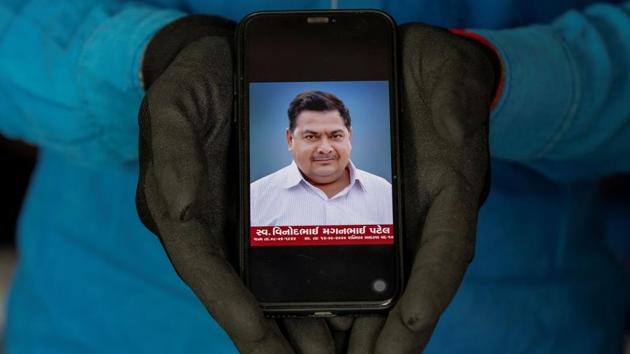 Dixit Vinodbhai Patel,19, a student, shows a picture of his father Vinodbhai Maganbhai Patel, a shopkeeper, who died of Covid-19, in Ahmedabad on September 25. “After my father’s death, all responsibilities are on my head as my father was the only earning member in our family. My college is closed at the moment, but when it starts, I will quit my studies to take care of my family,” his son told Reuters. (Amit Dave / REUTERS)