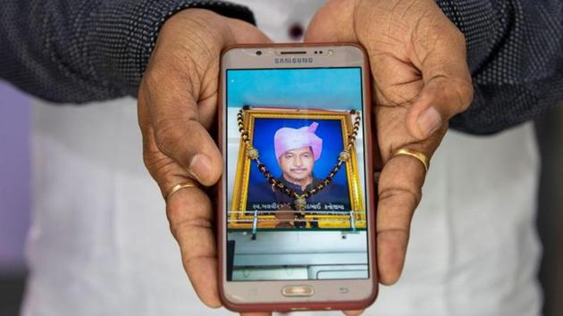 Yogesh Kanojia,36, a businessman, shows a picture of his father Balbir Mulchand Kanojia, also a businessman, who died of Covid-19, in Ahmedabad on September 25. “In our country there is almost no healthcare system, it is zero percent, the government advises people to drink warm water and take Ayurvedic medicine and live at your own risk,” Kanojia told Reuters. (Amit Dave / REUTERS)
